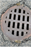 A round cast-iron catch-basin grate in pavement